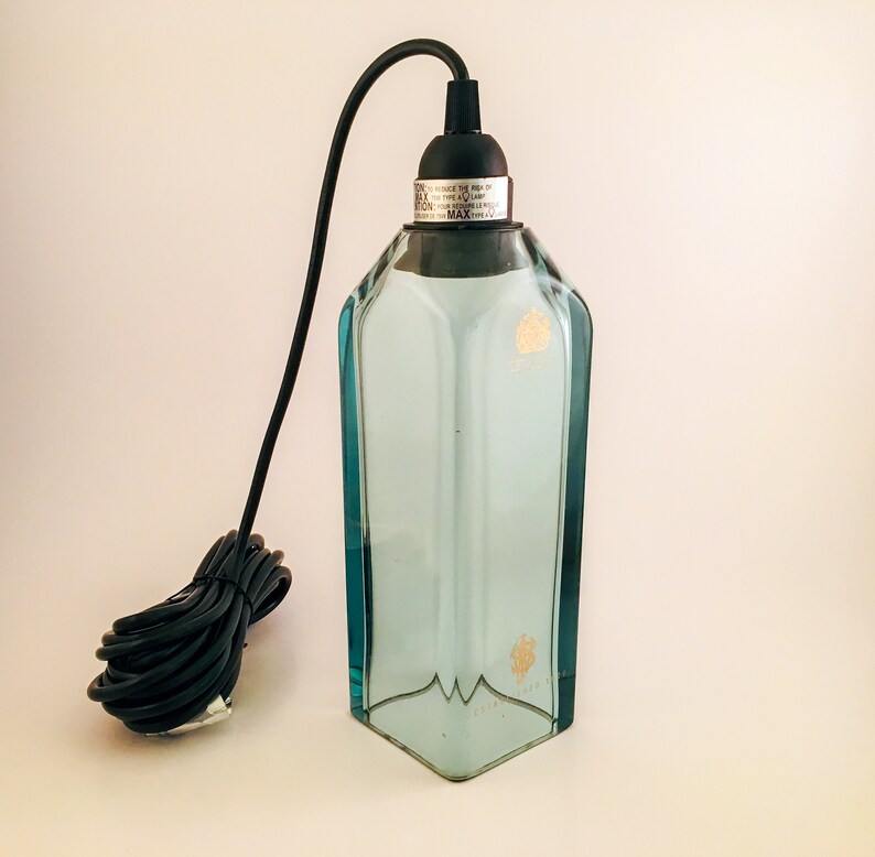 May include: A clear glass pendant light fitting with a black cord and a black metal cap. The glass is textured and has a light blue tint. The cap has the text "DO NOT EXCEED THE MAX. WATTAGE OF THE LAMP. CAUTION: REPLACEABLE BULB ONLY. MAX. WATTAGE 60W."