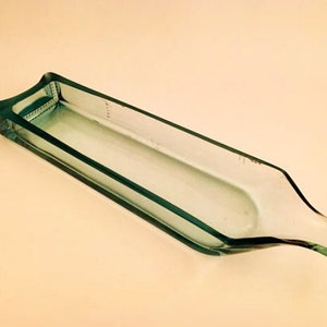 May include: A clear glass bottle that has been cut and repurposed into a serving dish. The bottle is rectangular in shape and has a rounded lip.
