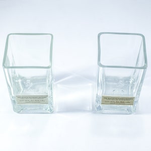May include: Two clear glass tumblers with square bases. The tumblers are empty and have a label on the bottom that reads "The Master Blender's Reserve, Finest Malt and Grain Whiskies, Est 1820, John Walker & Sons, Product of Scotland."