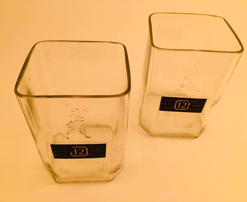 Op de afbeelding: Twee vierkante drinkglazen van helder glas met een 12 jaar oud whisky-etiket op de bodem.