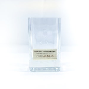 May include: A clear glass bottle with a label that reads "The Master Blender's Reserve Finest Malt and Grain Whiskies Est: 1820 John Walker & Sons Product of Scotland".