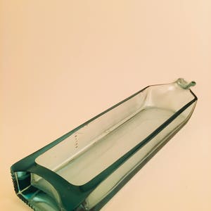 May include: A teal blue glass dish made from a recycled bottle. The dish is rectangular and has a smooth, polished surface.