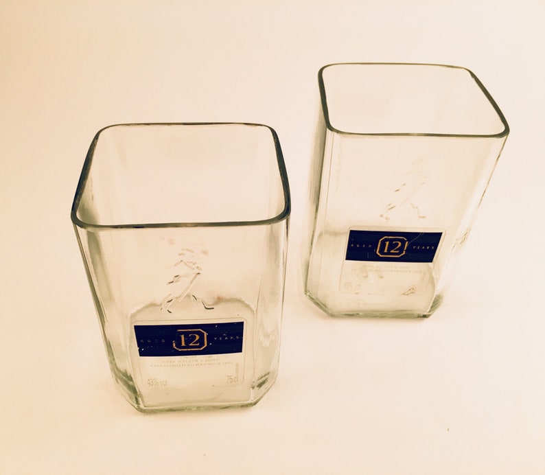 Op de afbeelding: Twee vierkante flessen van helder glas met een blauw etiket waarop "12 Years" staat en een nummer "12" in een cirkel.