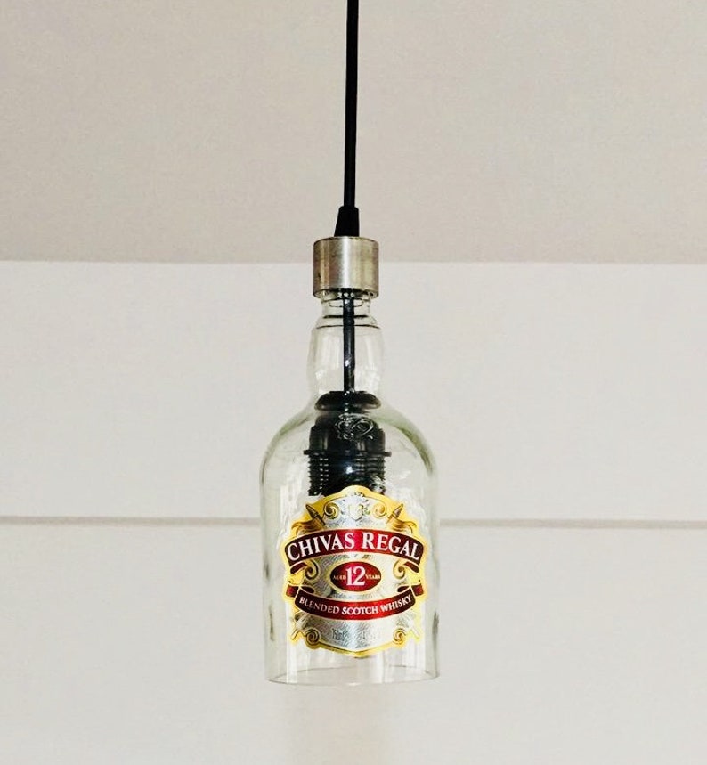 Peut inclure: Une suspension en verre transparent en forme de bouteille avec un cordon noir et un bouchon argent&eacute;. La bouteille porte une &eacute;tiquette indiquant "Chivas Regal 12 ans Blended Scotch Whisky".