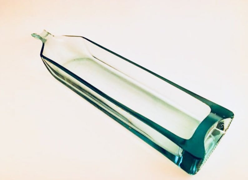 May include: A clear glass rectangular dish with a teal blue rim. The dish is empty and has a slight curve to it.