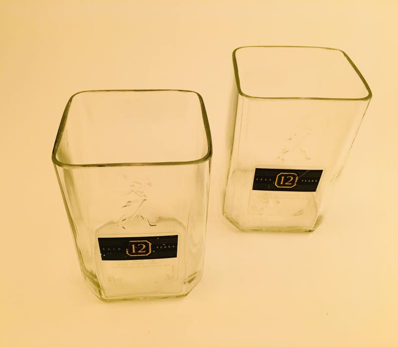 Op de afbeelding: Twee heldere glazen tumblers met een vierkante vorm en een 12-jarig whisky-etiket op de bodem.