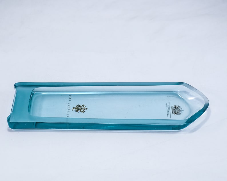May include: A light blue glass tray with rounded edges and a raised lip. The tray has a clear centre and a light blue border. The text "ESTABLISHED 1881" is printed on the tray.