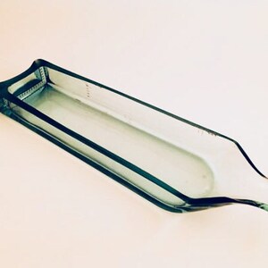 May include: A clear glass serving dish shaped like a bottle. The dish is made from recycled glass and has a smooth, polished finish.