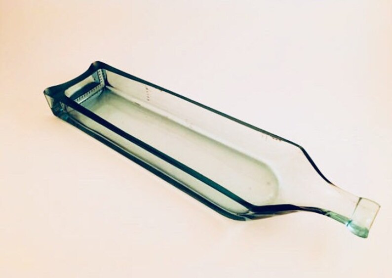 May include: A clear glass serving dish shaped like a bottle. The dish is made from recycled glass and has a smooth, polished finish.