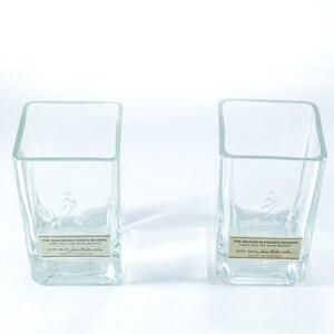 May include: Two clear glass square bottles with labels that read "The Master Blender's Reserve" and "Est 1820 John  Malt & Grain Whiskies".