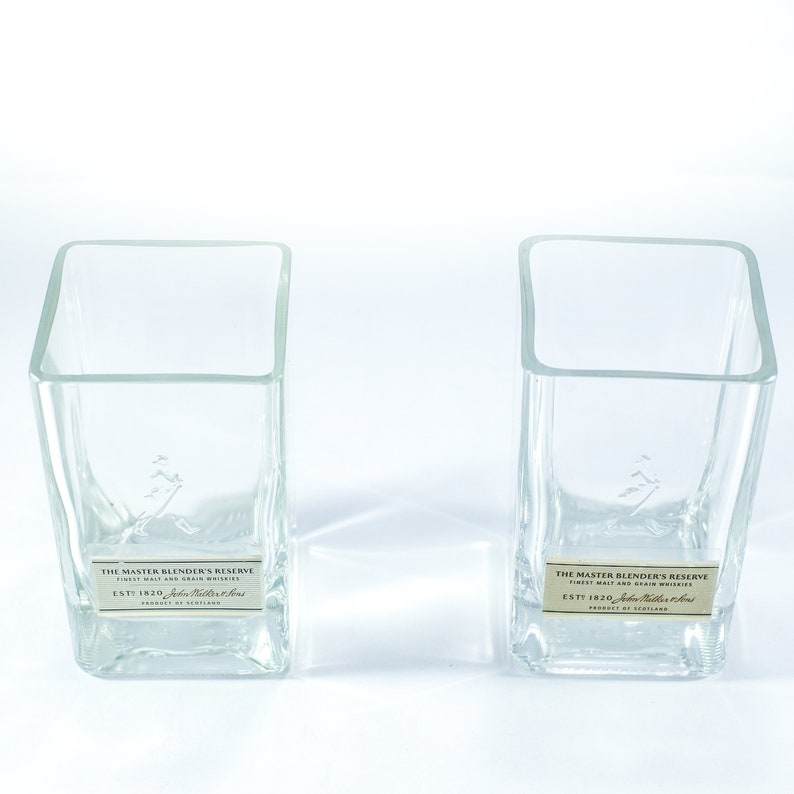 May include: Two clear glass square bottles with labels that read "The Master Blender's Reserve" and "Est 1820 John  Malt & Grain Whiskies".