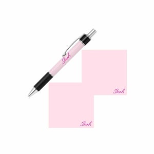 May include: A pink personalized notepad with the name "Sarah" written on it. A pink pen with a black barrel and the name "Sarah" written on it is lying on top of the notepad.