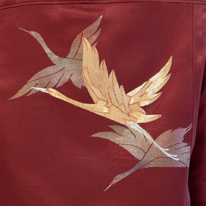 May include: A maroon jacket with a gold and silver embroidered design of two cranes in flight.