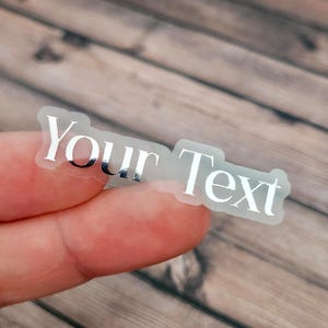 A transparent label sticker held between fingertips