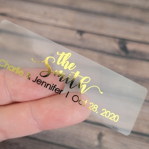 Peut inclure: Autocollant en plastique transparent avec lettrage en feuille d'or. Le texte indique "the Smith, Charlie & Jennifer | Oct 28, 2020".