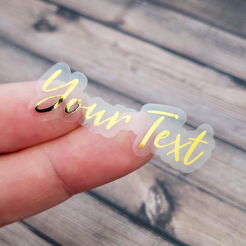 A transparent label sticker held between fingertips