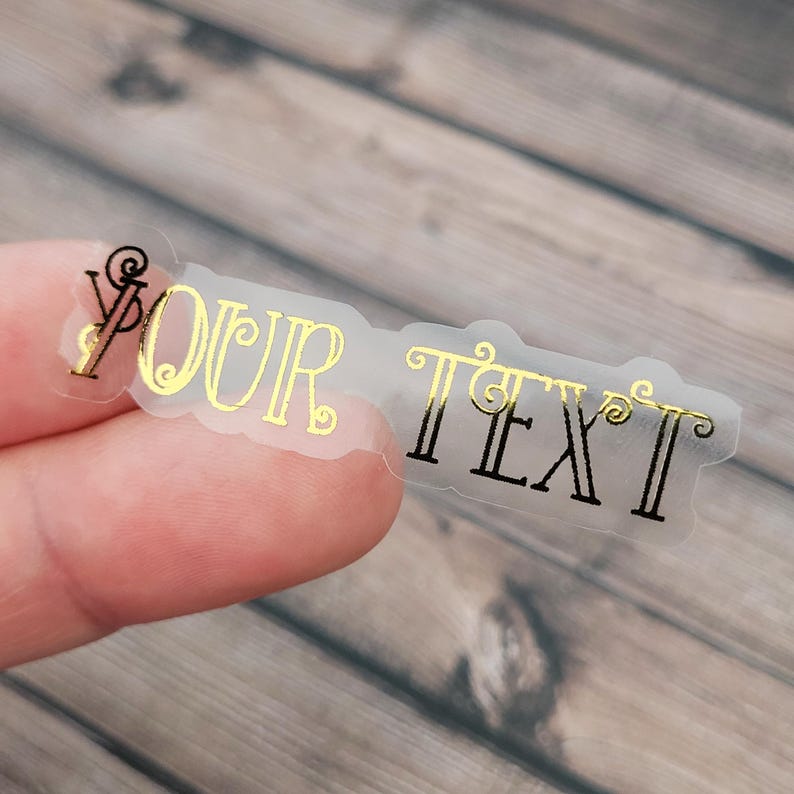 A transparent label sticker held between fingertips