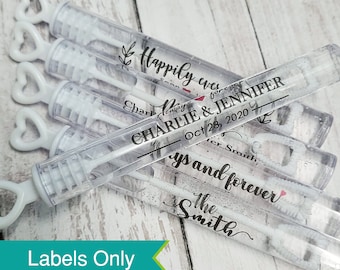 May include: Wedding bubble wands with personalized labels. The labels are black and white with a red heart and the text "Happily ever after, Charlie & Jennifer, Oct 28, 2020, Always and forever, The Smiths".