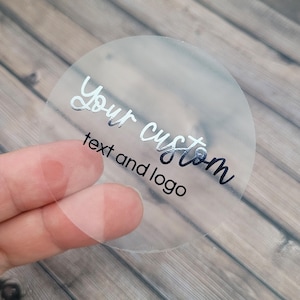 May include: Clear round sticker with silver foil lettering that says "Your custom text and logo".