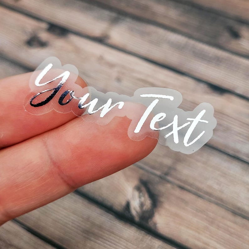 A transparent label sticker held between fingertips