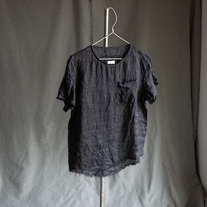 Op de afbeelding: Een donkergrijs linnen T-shirt met een klein zakje aan de linkerkant. Het shirt heeft een losse pasvorm en een licht gefranst zoom.