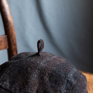 May include: A dark brown wool beret with a small loop on top.