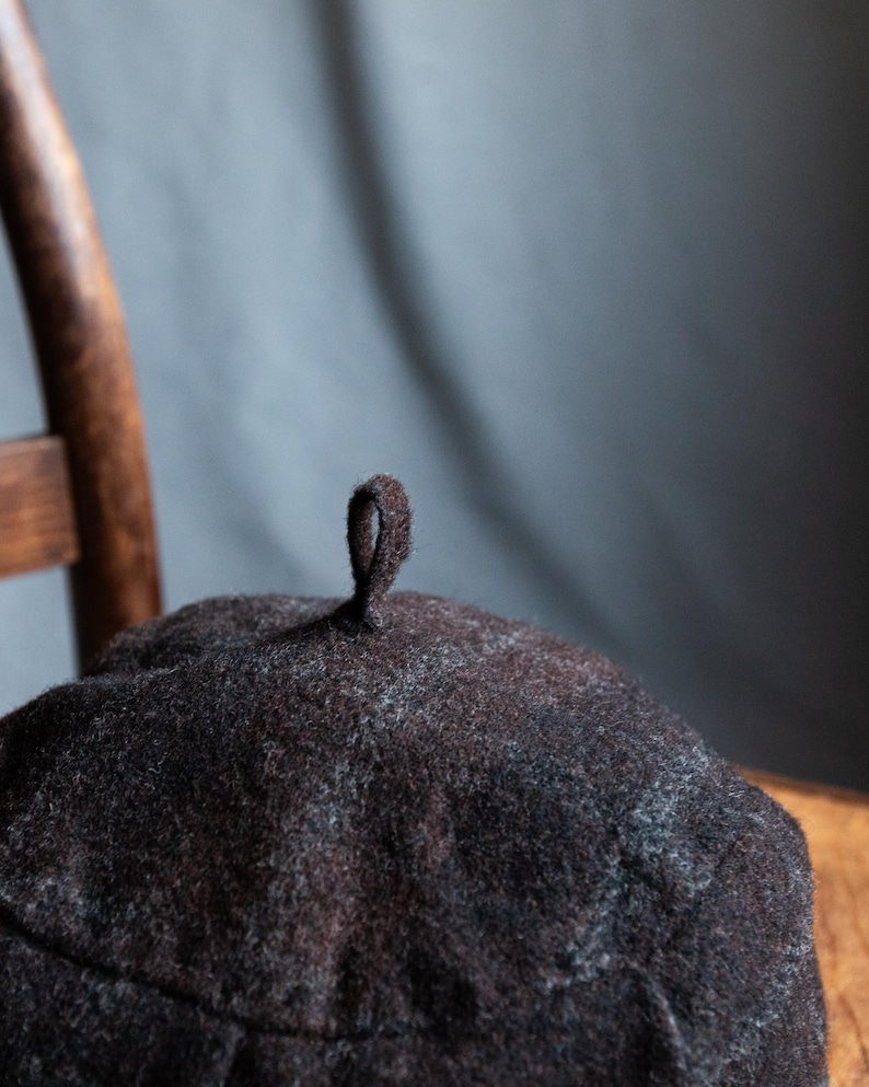 May include: A dark brown wool beret with a small loop on top.