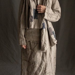 May include: A long, brown linen dress with a patchwork design and frayed edges. The dress has a matching scarf with a similar patchwork design.