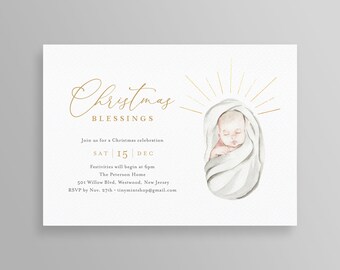 May include: A cream-colored Christmas invitation with gold script text reading "Christmas Blessings." It features a watercolor illustration of a baby wrapped in a white blanket, with gold rays emanating from behind. The invitation includes event details.