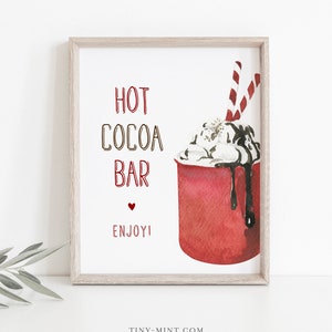 Puede incluir: Una impresión enmarcada con las palabras "HOT COCOA BAR" en rojo y marrón, y "ENJOY!" en rojo. La imagen presenta una ilustración en acuarela de una taza roja de chocolate caliente con crema batida, salsa de chocolate y pajitas a rayas.