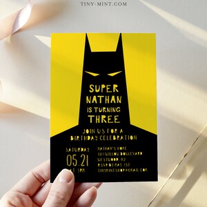 May include: A yellow and black birthday invitation with a Batman silhouette. The text reads "Super Nathan is turning Three. Join us for a birthday celebration. Saturday 05.21 at 3PM. Nathan's Home 501 Willow Boulevard Westwood, NJ RSVP by May 1st TinyMintShop@gmail.com"