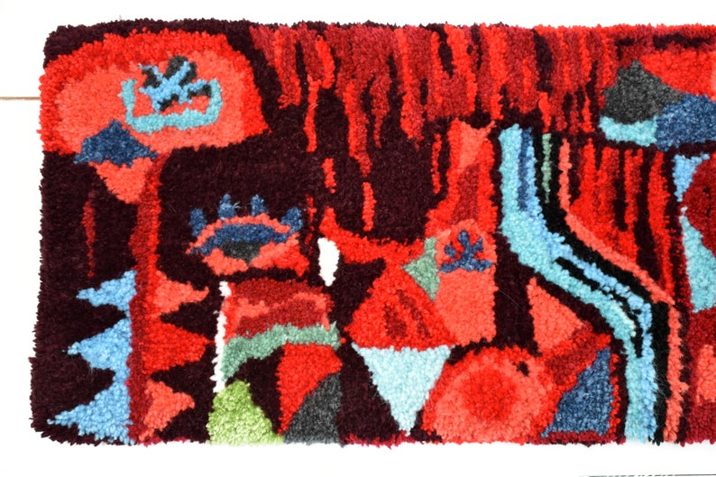 Puede incluir: Una alfombra abstracta colorida con un dise&ntilde;o texturizado tejido a mano. La alfombra presenta tonos de rojo, azul, verde y negro.