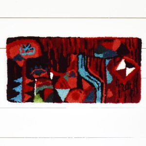 Puede incluir: Una alfombra abstracta colorida con un dise&ntilde;o rojo, azul, verde y negro. La alfombra est&aacute; hecha de un material grueso y texturizado y tiene un patr&oacute;n geom&eacute;trico.
