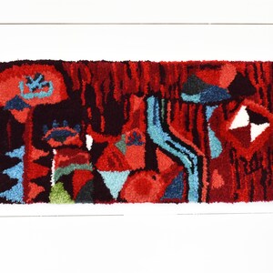 Puede incluir: Una alfombra abstracta colorida con un dise&ntilde;o rojo, azul y verde. La alfombra est&aacute; hecha de un material grueso y texturizado y tiene un patr&oacute;n geom&eacute;trico.