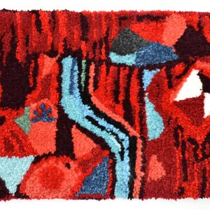 Puede incluir: Alfombra abstracta con un esquema de color rojo, azul y blanco. La alfombra tiene un aspecto texturizado y tejido a mano.