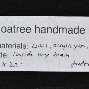 Puede incluir: Una tarjeta blanca con texto escrito a mano en negro. El texto dice "Y goatree handmade", "materials: wool, acrylic yarn, cotton", "title: Inside my brain", "114 x 224", y "goatree '22".