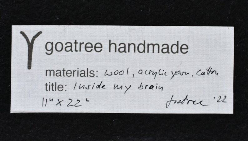 Puede incluir: Una tarjeta blanca con texto escrito a mano en negro. El texto dice "Y goatree handmade", "materials: wool, acrylic yarn, cotton", "title: Inside my brain", "114 x 224", y "goatree '22".