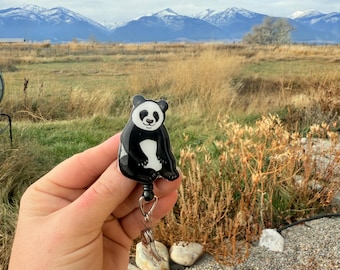 May include: A black and white panda bear retractable badge reel. The badge reel has a black cord and a clear plastic clip. The text "No AI used in my Art" is visible in the background.