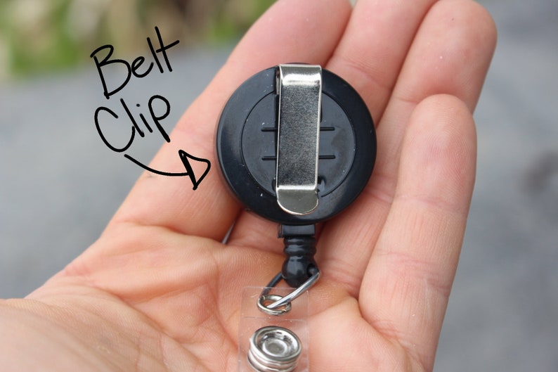 May include: Black retractable badge holder with a metal belt clip. The holder has a clear plastic ring for attaching a badge or ID card.