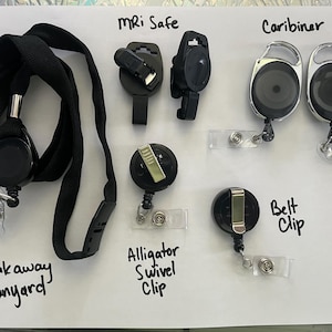 May include: Assortment of black badge holders and lanyards. Includes a breakaway lanyard, MRI safe clips, carabiner style holders, alligator swivel clips, and belt clip style holders. Text labels identify each type.