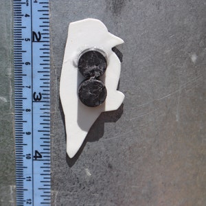 Op de afbeelding: Witte pingu&iuml;n-vormige magneet met twee ronde zwarte magneten aan de achterkant.