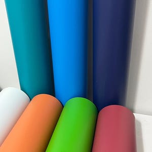May include: A collection of brightly coloured cylindrical objects. The colours include teal, blue, navy, white, orange, green, and red. Some stand upright, others are angled. The objects are arranged in a diagonal pattern.