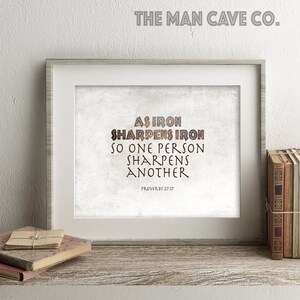 Peut inclure: Une impression encadrée avec un fond blanc et un design texturé brun. L'impression présente le texte "Comme le fer aiguise le fer, ainsi un homme aiguise son prochain" et la référence biblique "Proverbes 27:17".