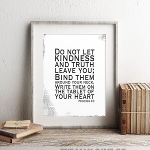 Peut inclure: Une impression noir et blanc encadrée avec le texte "Ne laisse pas la gentillesse et la vérité te quitter ; lie-les autour de ton cou, écris-les sur la tablette de ton cœur. Proverbes 3 : 3". L'impression est sur une étagère en bois avec une pile de livres et une horloge.