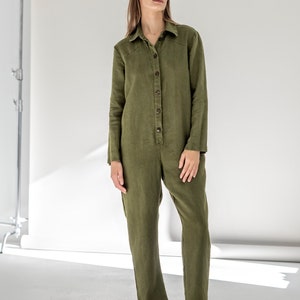 May include: A long-sleeved, olive green linen jumpsuit with a button-up front and a collared neckline.