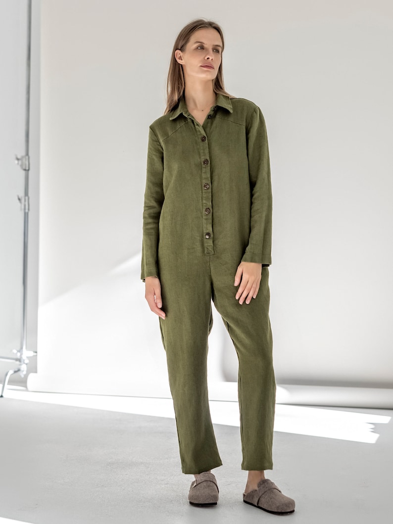 May include: A long-sleeved, olive green linen jumpsuit with a button-up front and a collared neckline.