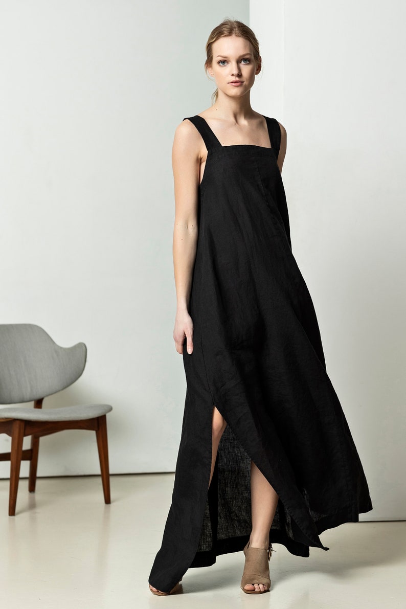 May include: A black linen maxi dress with a square neckline and thin straps. The dress has a side slit and a relaxed fit.