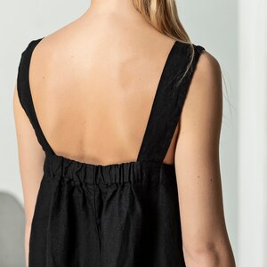 May include: A black linen dress with thin straps and a gathered waist.