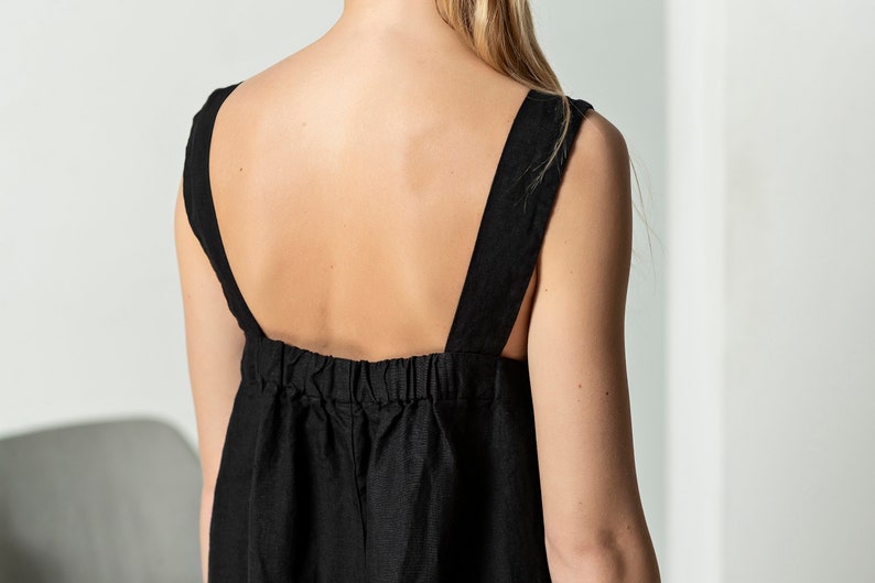 May include: A black linen dress with thin straps and a gathered waist.