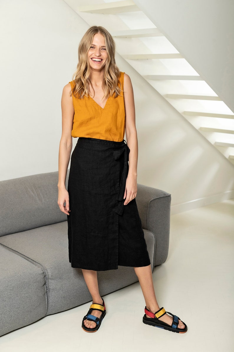 Wrap linen skirt, ends just below the knee, in black color. Full-height front photo.